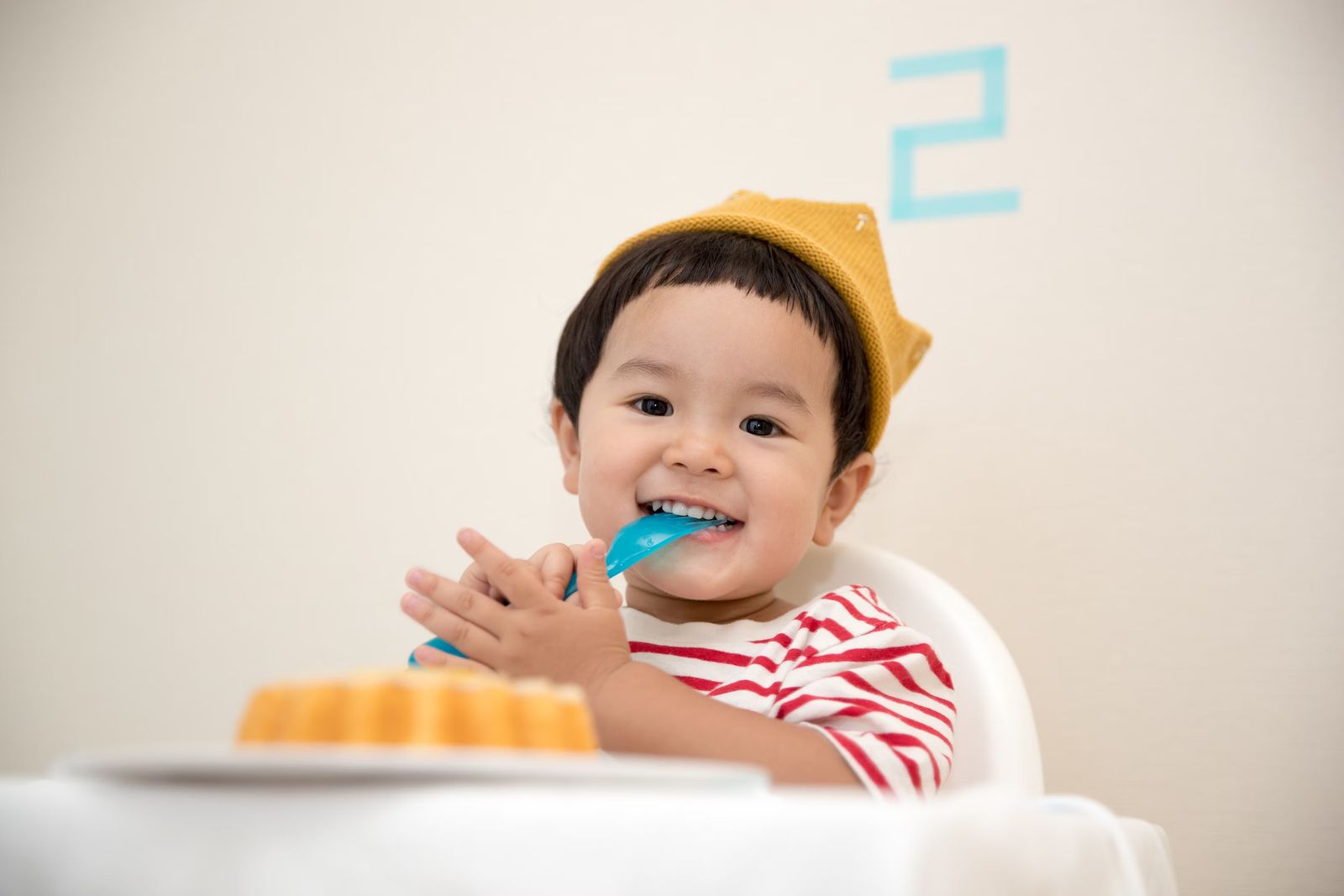 戴著紙皇冠、坐在兒童餐椅上微笑的幼兒